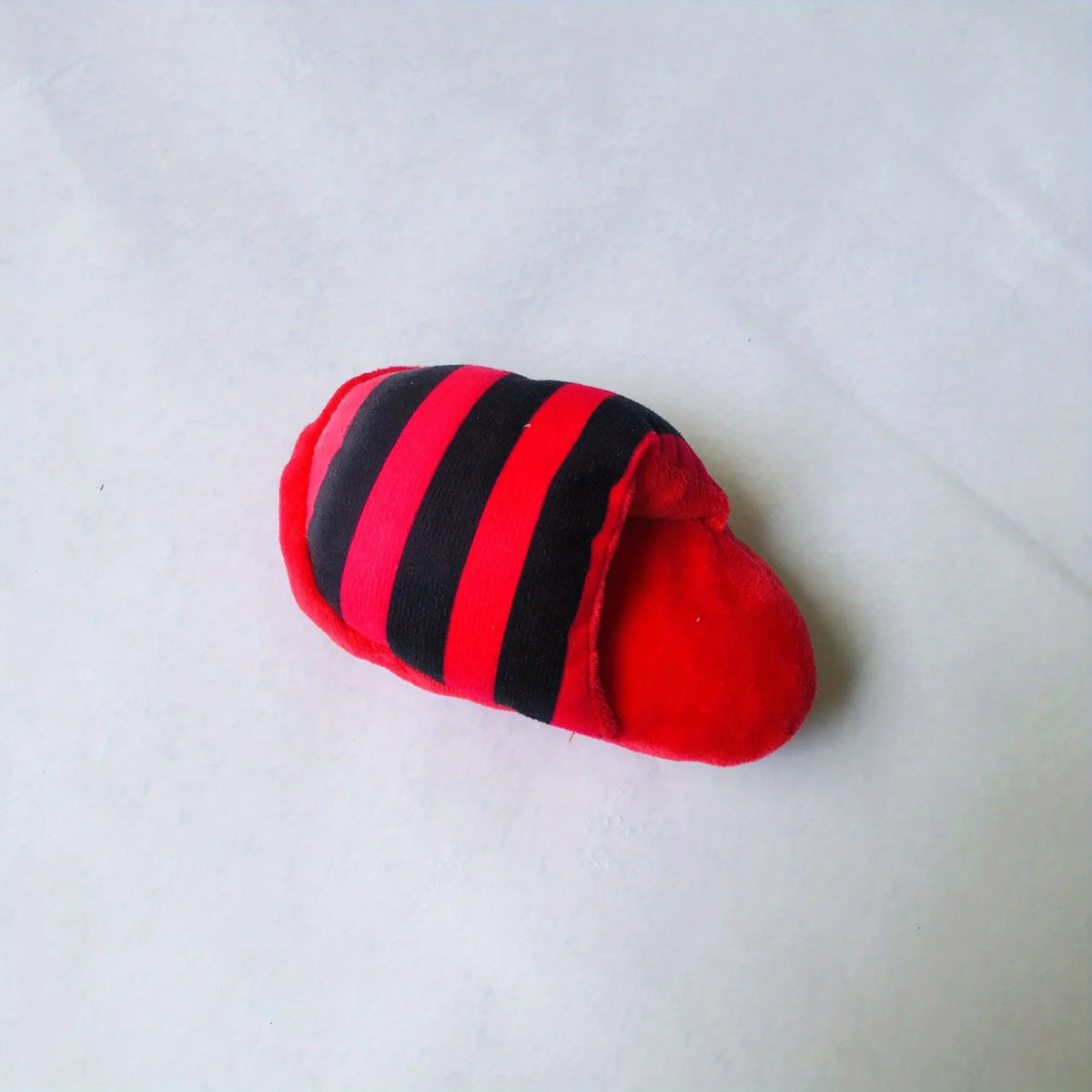 A red and black striped plush dog chew toy shaped like a slipper.
