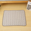 A gray quilted cooling mat designed for pet beds, placed on a light wooden surface.