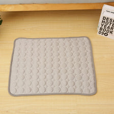 A gray quilted cooling mat designed for pet beds, placed on a light wooden surface.