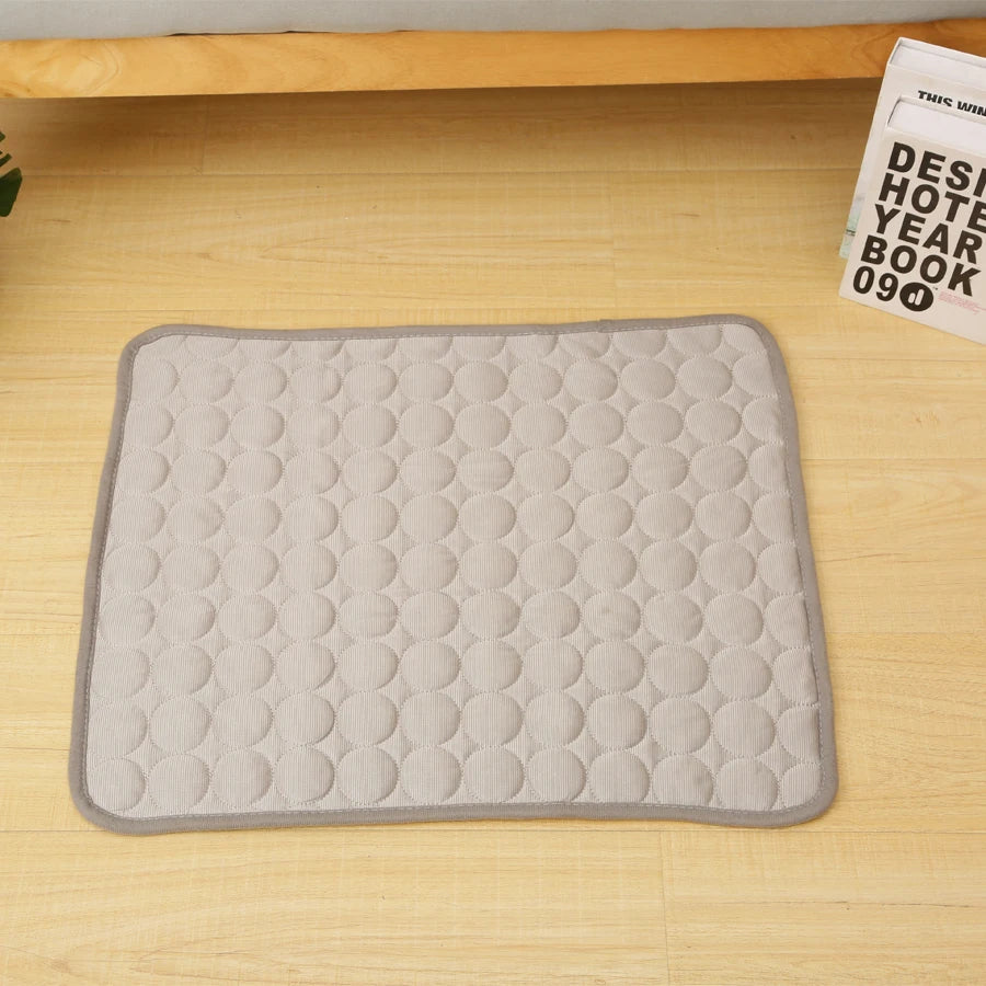 A gray quilted cooling mat designed for pet beds, placed on a light wooden surface.