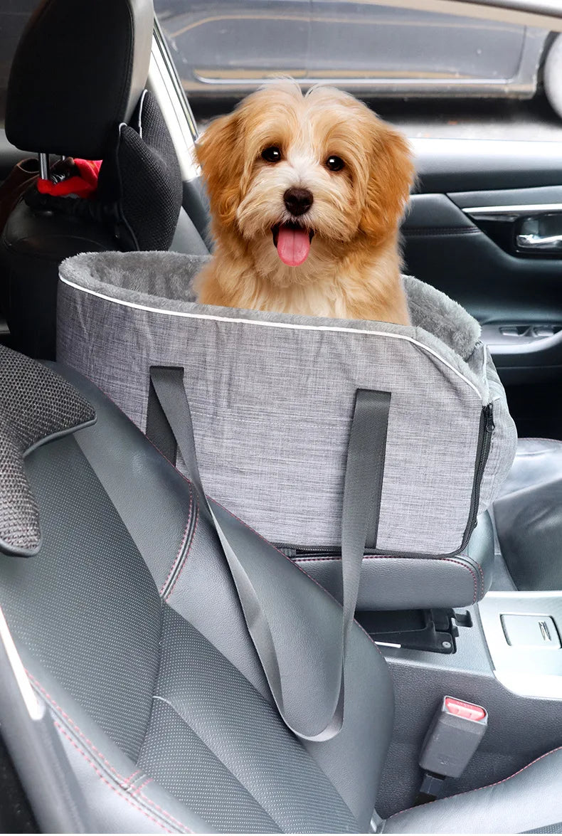 A golden-colored dog is resting in a gray portable pet car bed with safety straps inside a car.