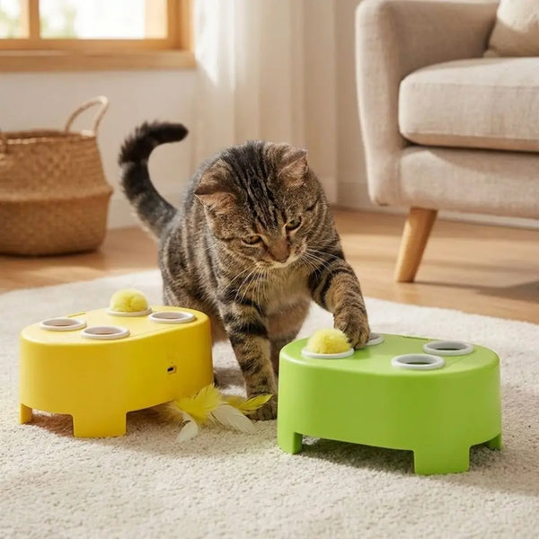 A tabby cat is interacting with a yellow and green interactive toy designed for play.