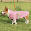 A light pink waterproof dog raincoat with yellow reflective stripes is worn by a Shiba Inu dog outdoors.