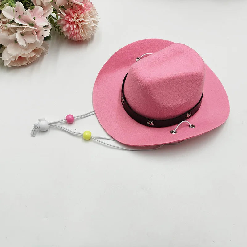 A pink felt cowboy hat with a black band and decorative string ties is shown next to pink flowers.