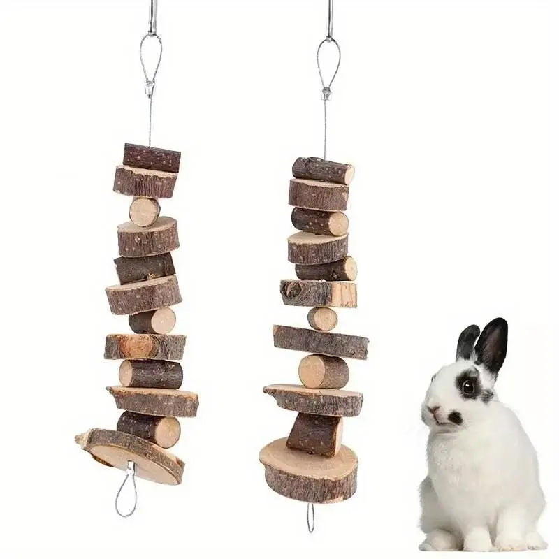 Ein weißer Hase sitzt neben einem Stapel aus Holzknabbernspielzeug.