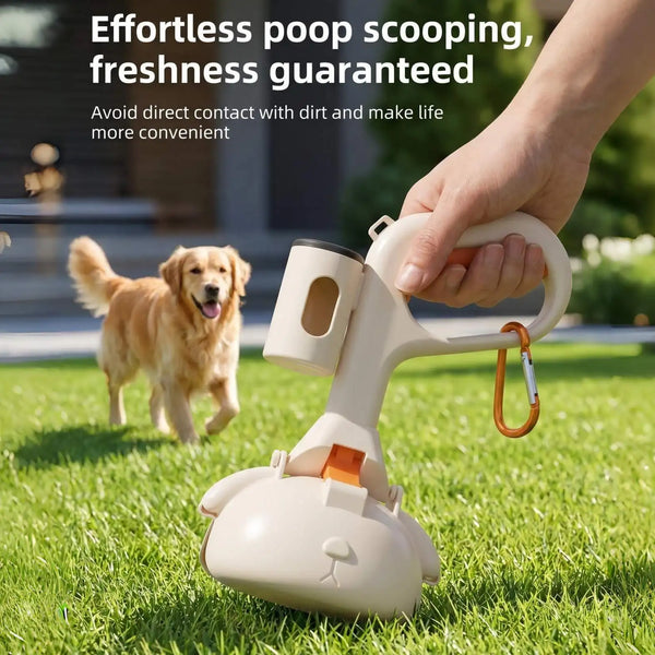A hand is using a beige portable pet poop scooping tool on a green lawn with a dog in the background.