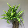 A vibrant artificial tropical palm plant with variegated green and yellow leaves displayed on a wooden base.