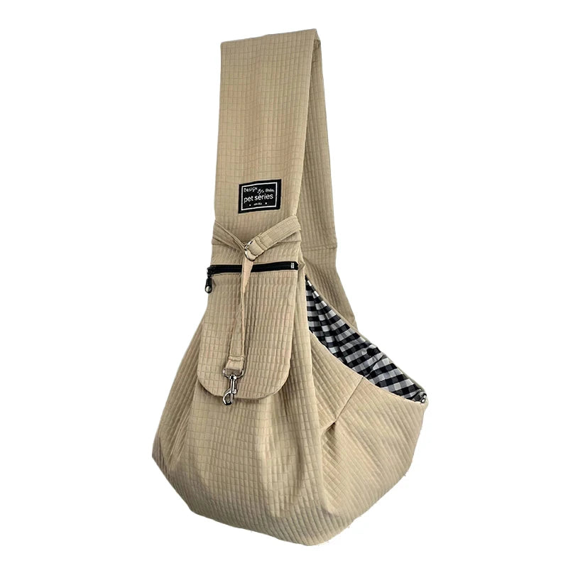 A beige quilted crossbody pet carrier bag with a black trim and checkered fabric detail.