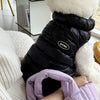 Schwarze Pufferjacke mit weißem Kunstpelz-Kapuze auf hellem Sofa.