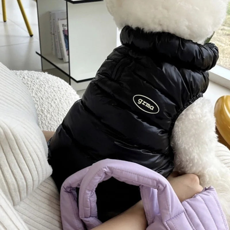 Schwarze Pufferjacke mit weißem Kunstpelz-Kapuze auf hellem Sofa.