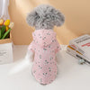 A fluffy gray dog wearing a pink waterproof summer raincoat with small green floral patterns.