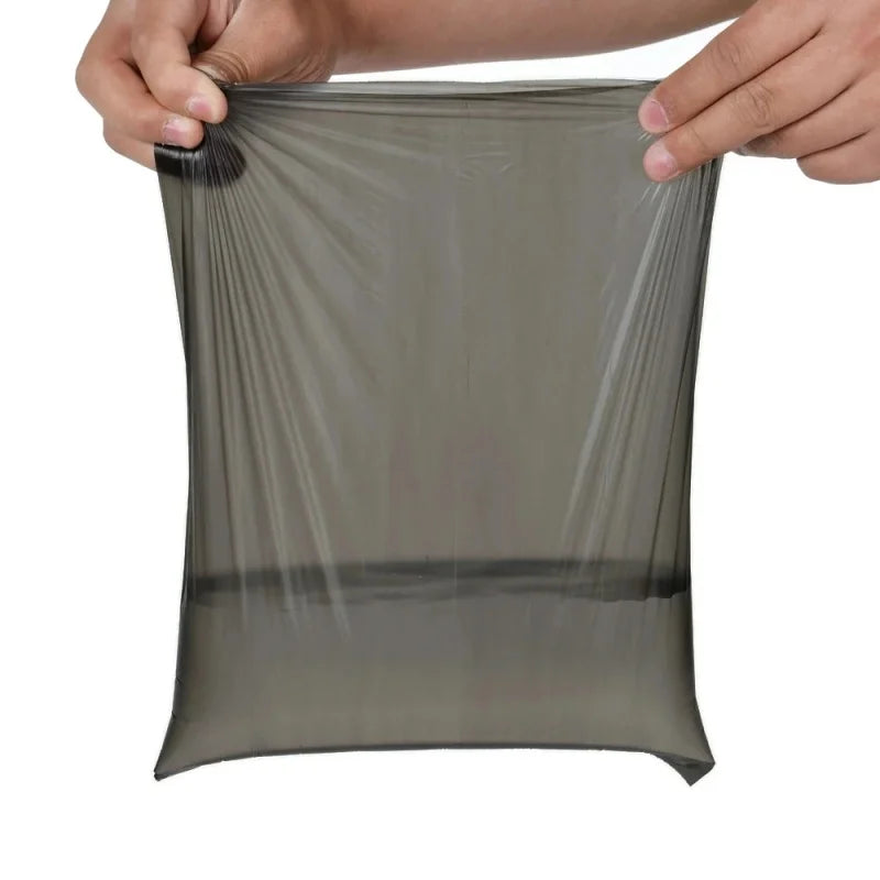 A hand is holding a clear, flexible biodegradable dog poop bag with an easy-tear design.