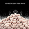 A close-up view of light pink bio balls filter media particles piled up, showing a porous texture.