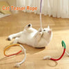 A white cat is playing with a purple cat teaser rope and an orange ring toy on a wooden floor.