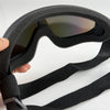 A hand holds a black adjustable dog pet safety goggle with tinted lenses.