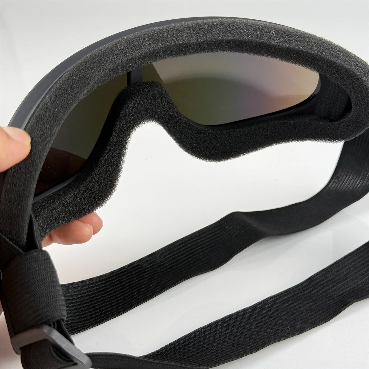 A hand holds a black adjustable dog pet safety goggle with tinted lenses.