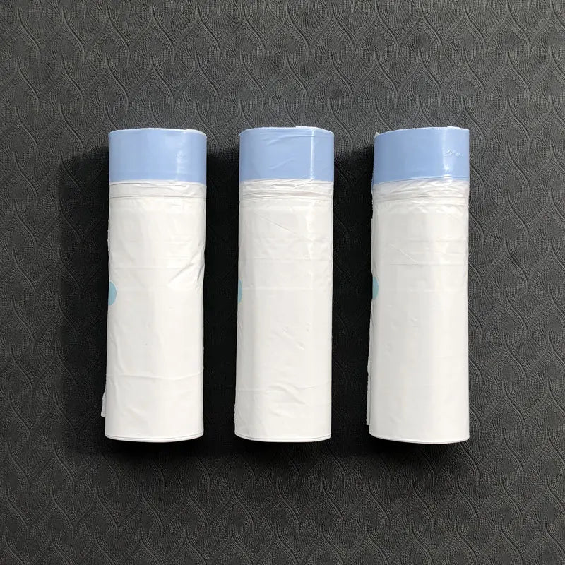 Trois rouleaux de sacs de littere en tissu blanc épais avec des dessus bleu clair, exposés sur une surface sombre.
