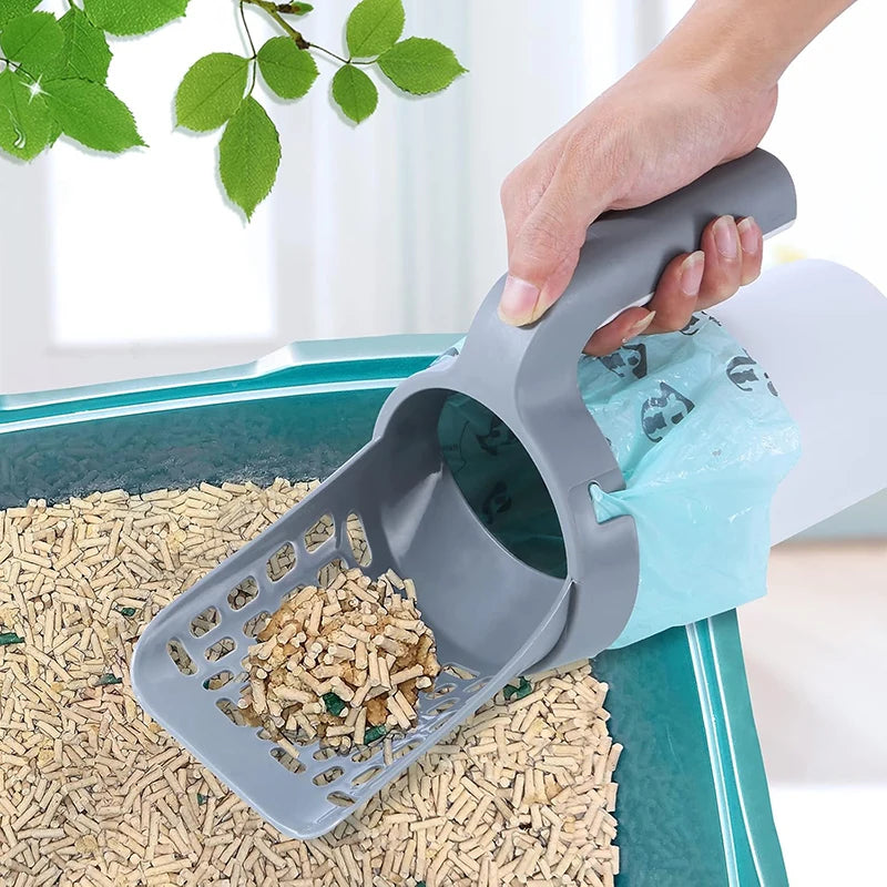 A hand is scooping pet litter from a tray using a gray reusable scoop and a blue waste bag.
