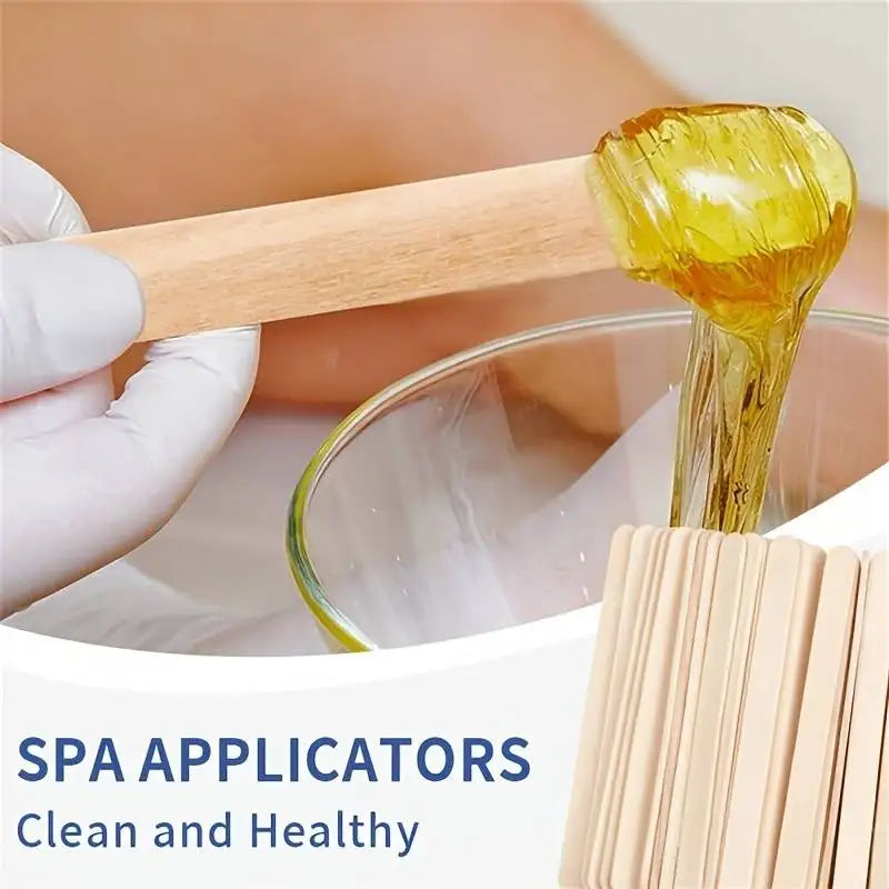 Eine Hand benutzt einen Holzaplikator, um geltes Öl auf eine Glasschale für Spa-Behandlungen aufzutragen.