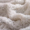 A close-up of a super soft, white and cream textured blanket with floral patterns.