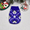 A navy blue knitted dog sweater featuring a white pattern of panda faces and stars, displayed with Christmas decorations.