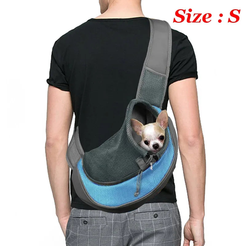 A person is wearing a gray breathable dog sling carrier with a small dog inside.