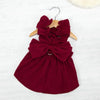 A deep burgundy vintage corduroy pet dress featuring a bow and ruffled detail, displayed on a wooden hanger.
