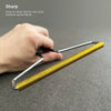 A hand is holding a yellow manual lint remover brush with a silver handle, demonstrating its use for removing fabric and pet 