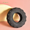 A black rubber tire toy resting on a pink surface.