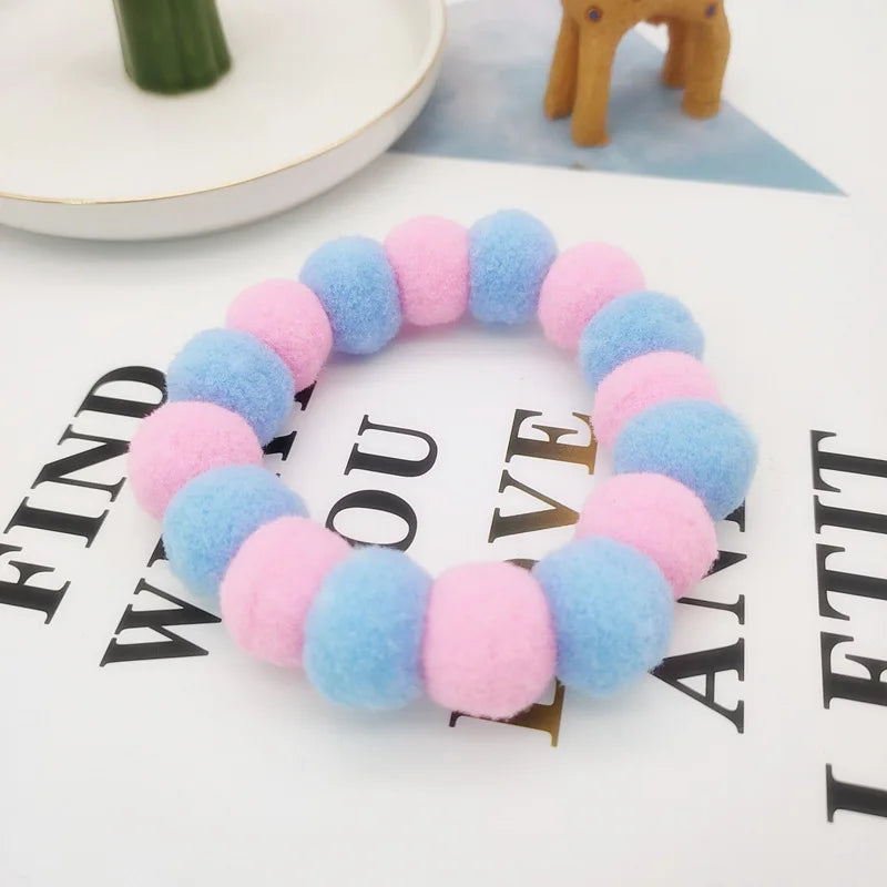 A colorful pet collar and bow tie set featuring fuzzy balls in shades of pink, blue, and purple.