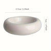 A white ceramic donut cat bowl with a smooth, rounded shape and a slight lip.