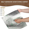 A close-up of a silver self-adhesive scratching carpet being peeled off a surface like glass or wood.