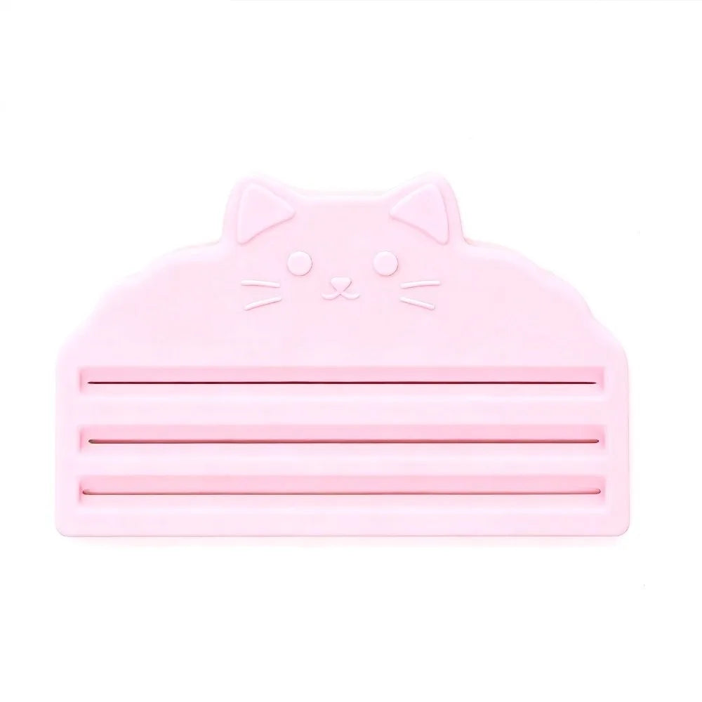 A pink reusable cat food pouch scraper shaped like a cat's head.