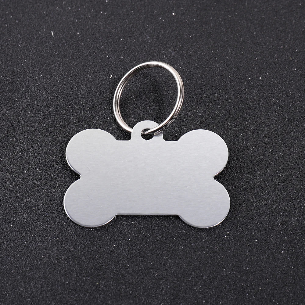 Silver bone-shaped dog ID tag with a circular keyring against a dark background.