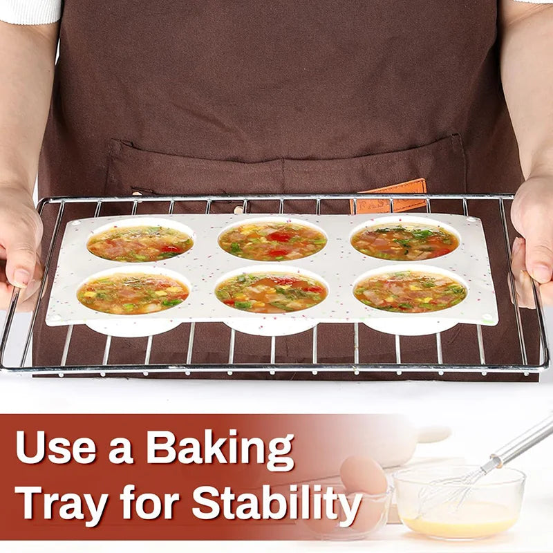 A baking tray holds multiple non-stick silicone egg molds for breakfast sandwiches and baking.