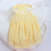 Robe jaune avec une couronne florale blanche pour petits chats, posée sur un tissu blanc.