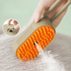 A hand holds an orange and beige 3-in-1 electric pet grooming brush with a steam comb, demonstrating its use on fur.