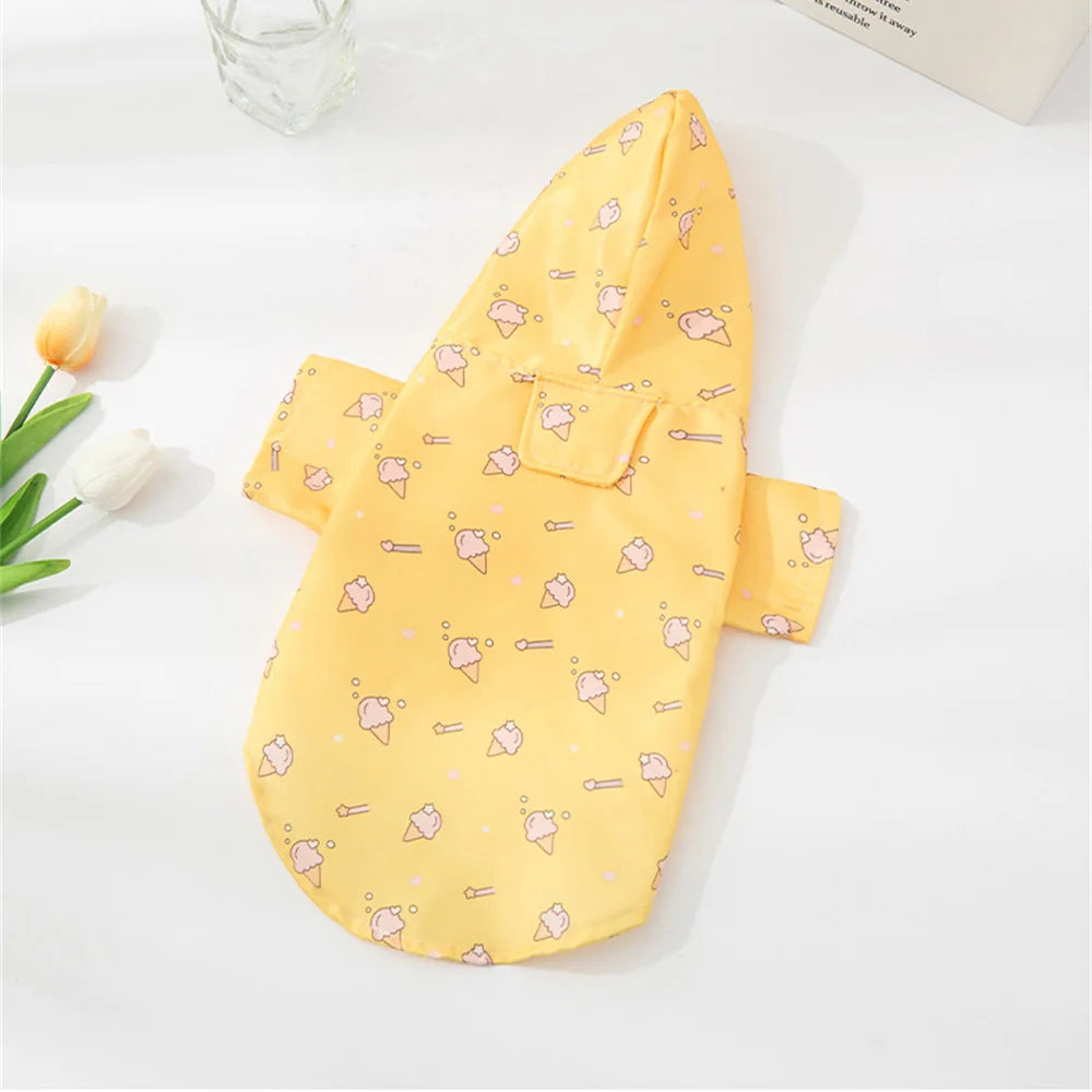A yellow cartoon printed dog raincoat with a pocket lying on a white surface.