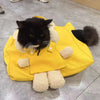 A black cat is sitting inside a yellow breathable mesh pet carrier backpack with white fluffy lining.