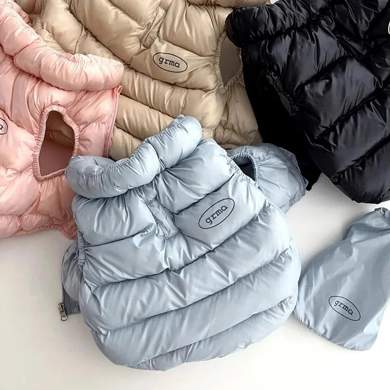 Ein Stapel weicher, gesteppter Winterjacken für Hunde und Katzen in rosa, beige und hellblauen Farben.