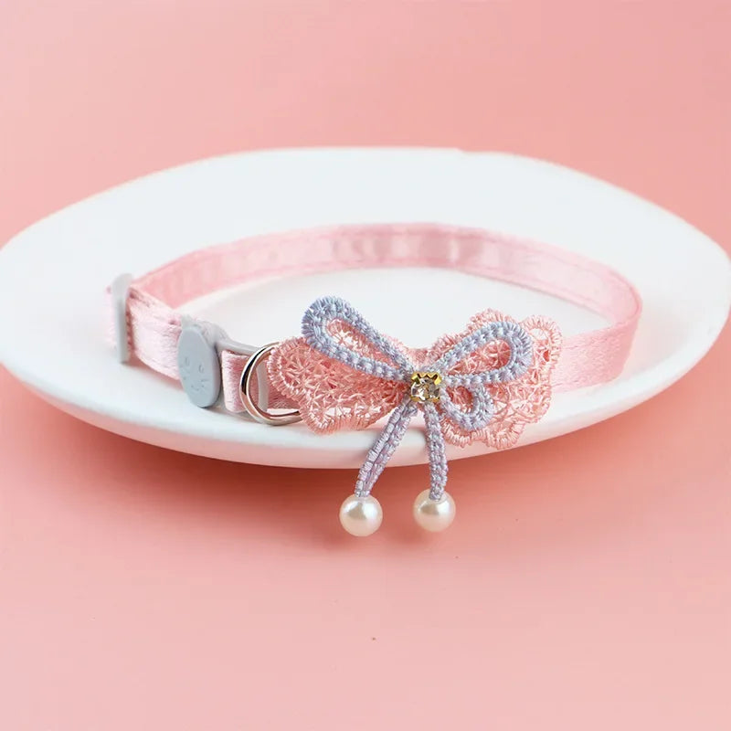 Rosa Spitzenhalsband für Haustiere mit Schleife und hängenden Perlen auf einer weißen Platte