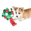 Ein kleiner Hund interagiert mit einem grünen Fleece-Snuffle-Spielzeug, gefüllt mit gerolltem rotem und weißem Stoff.