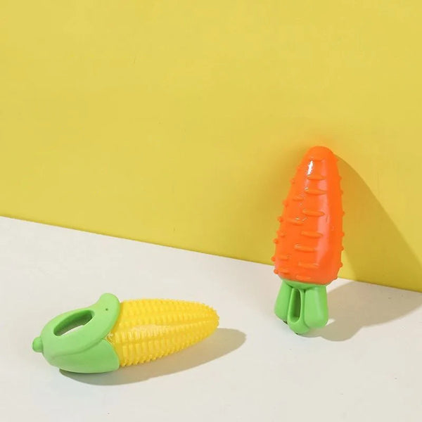 An orange carrot shaped squeaky chew toy for dogs resting on a white surface.