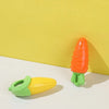 An orange carrot shaped squeaky chew toy for dogs resting on a white surface.