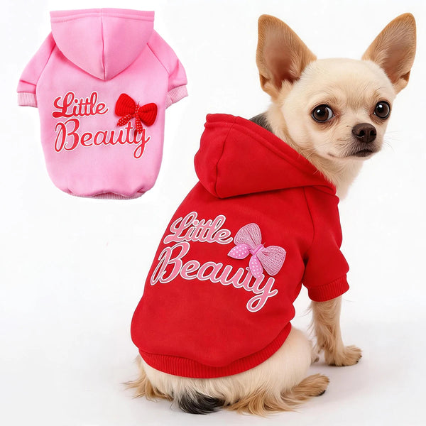 A small tan dog wearing a red hoodie with pink embroidery that reads Little Beauty
