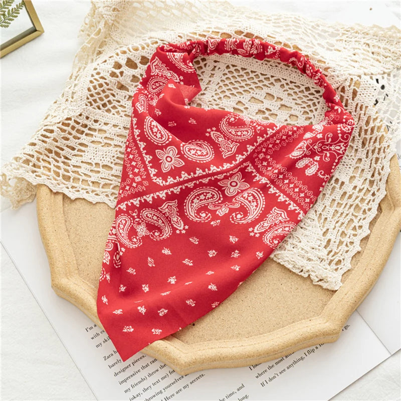 Diadema elástica con estampado floral roja drapeada sobre tela de ganchillo blanca.