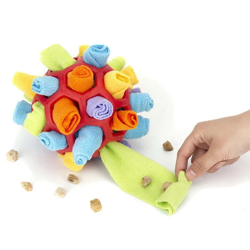 Buntes, kugelförmiges Fleece-Snuffle-Spielzeug mit orange-blauen Stoffbällen wird von einer Hand gehalten.