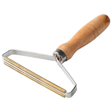A manual lint remover tool with a wooden handle and metal strips for removing lint from clothing.