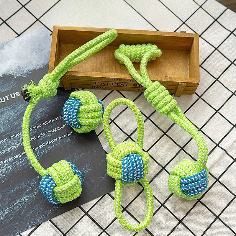 Green rope ball dog toys with blue accents displayed on a wooden tray.