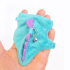 A turquoise felt vest harness with a purple strap and silver charm is held in a hand.